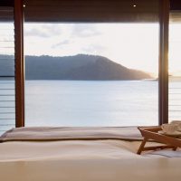 Resort & Villa Spa Room With White Bed And Glass Wall Overlooking Natural View 972x628 Relaxed-Living-Area-with-Glass-Wall-Theme-674x630